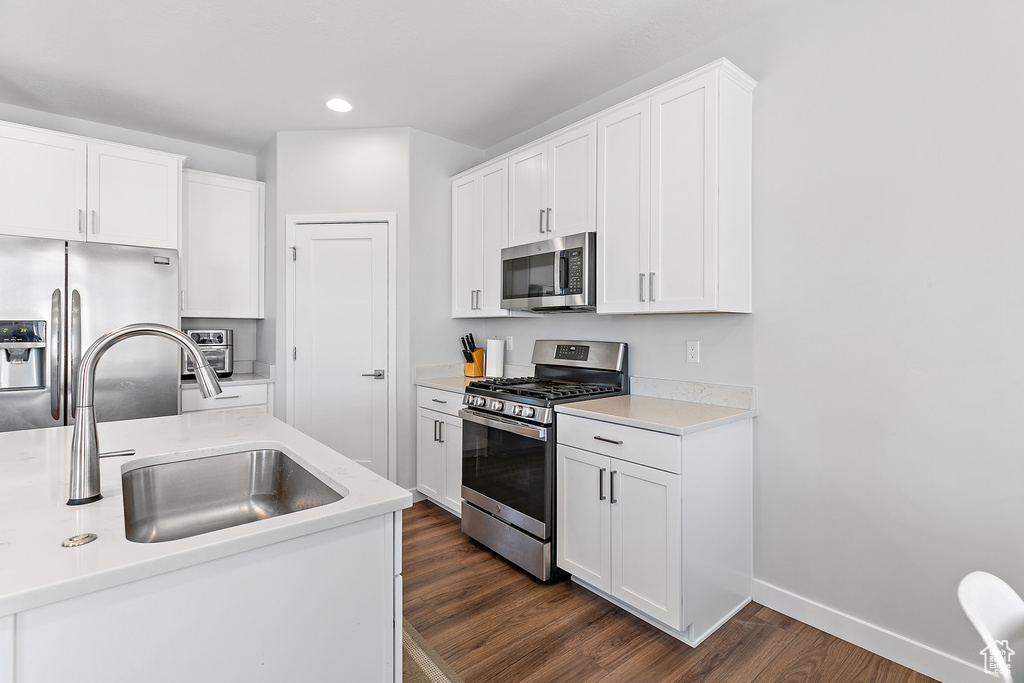 Kitchen featuring stainless steel appliances, dark wood finished floors, recessed lighting, a sink, and white cabinets