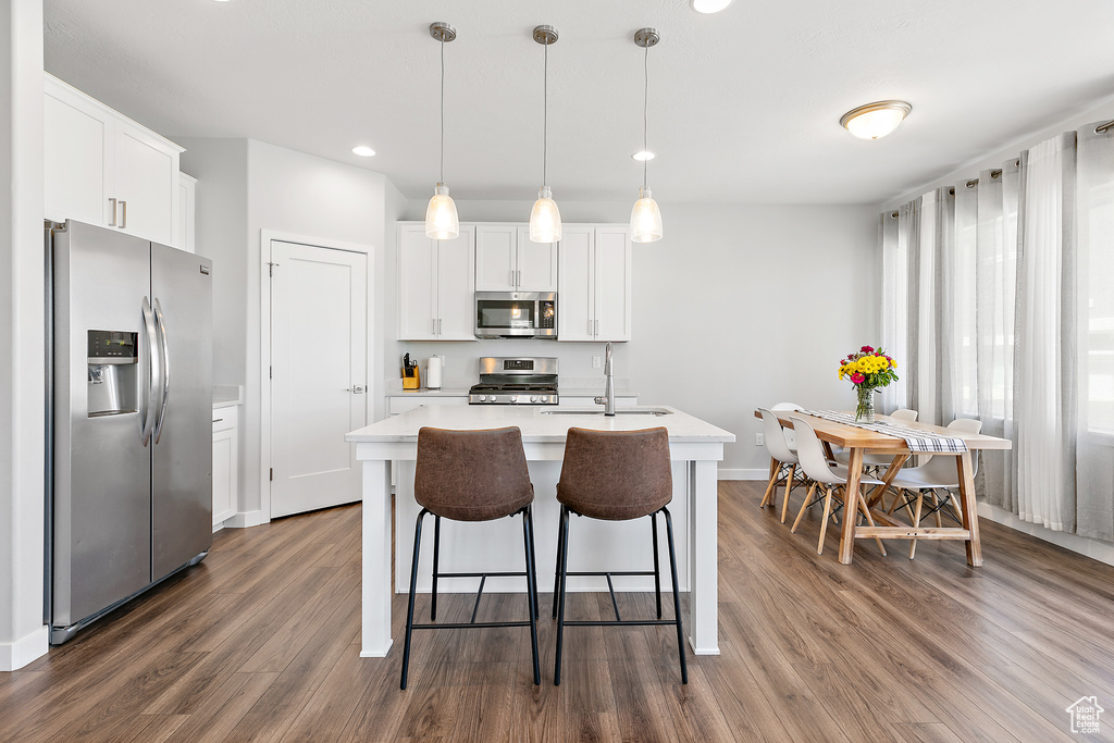 Kitchen featuring stainless steel appliances, a sink, light countertops, dark wood-style flooring, and white cabinetry
