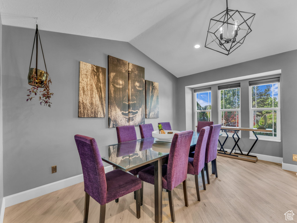 Dining area with vaulted ceiling, wood finished floors, baseboards, a chandelier, and recessed lighting
