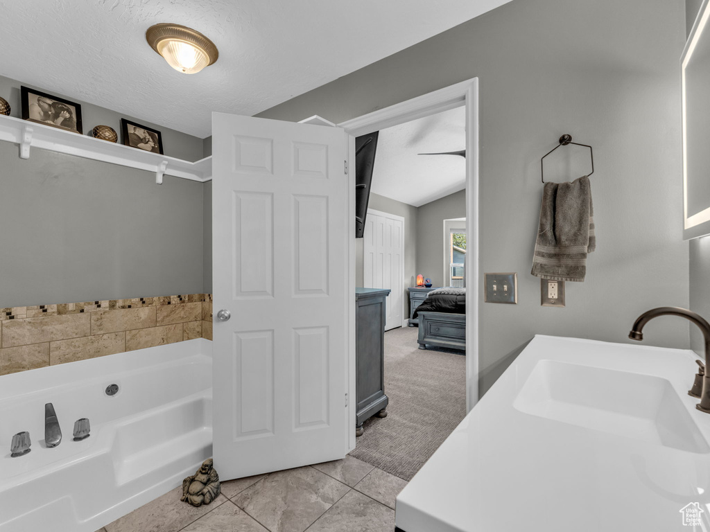 Ensuite bathroom featuring a garden tub, lofted ceiling, and vanity