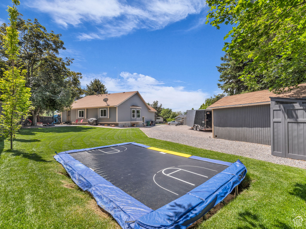 View of basketball court featuring a lawn and basketball court