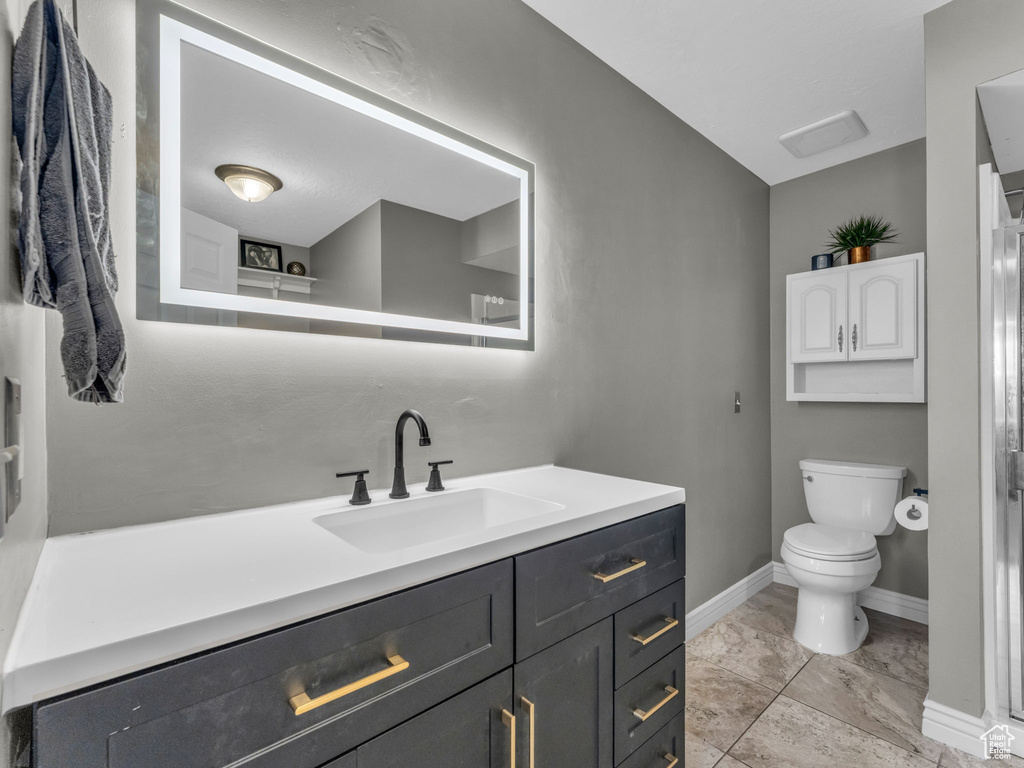 Bathroom featuring vanity, toilet, and baseboards