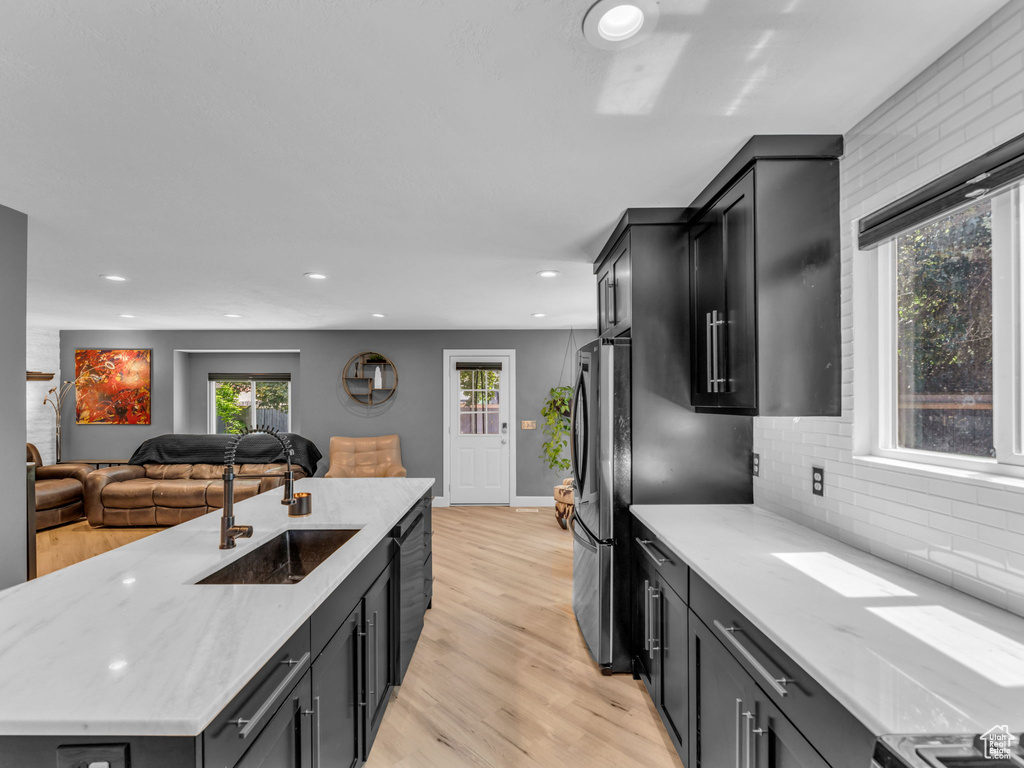 Kitchen with a sink, recessed lighting, light wood-style floors, backsplash, and open floor plan