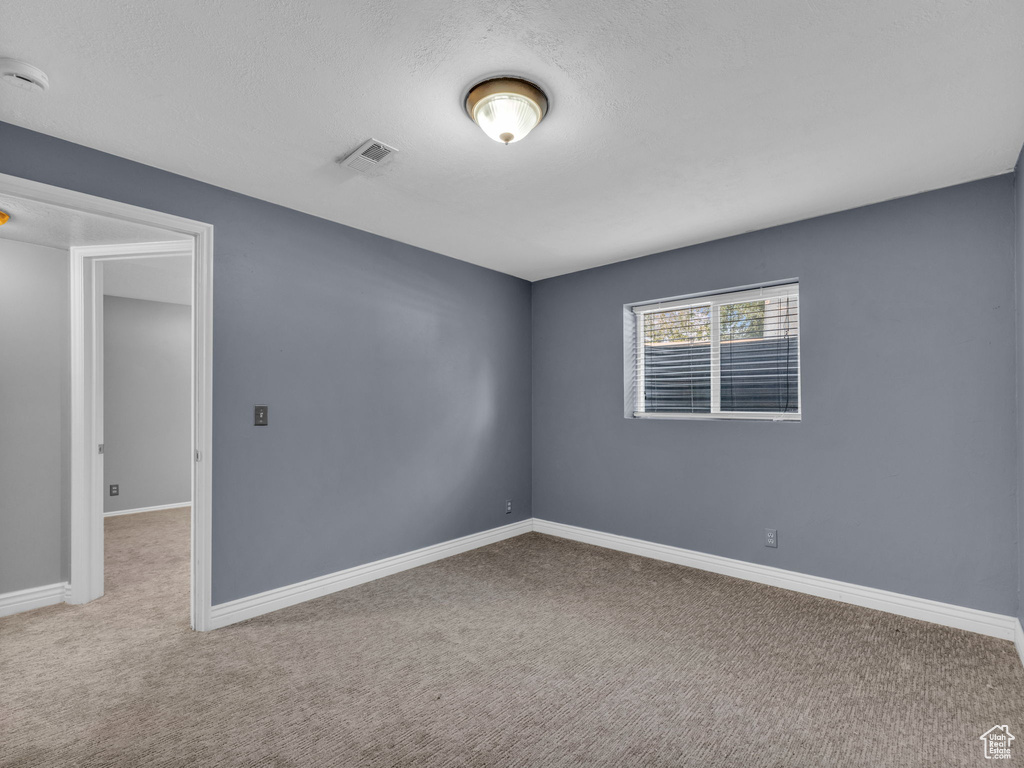 Empty room with carpet, a smoke detector, baseboards, and a textured ceiling