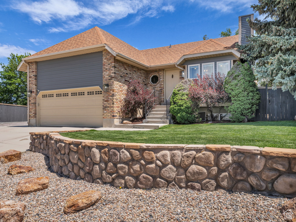 Single story home featuring concrete driveway, roof with shingles, brick siding, and a garage