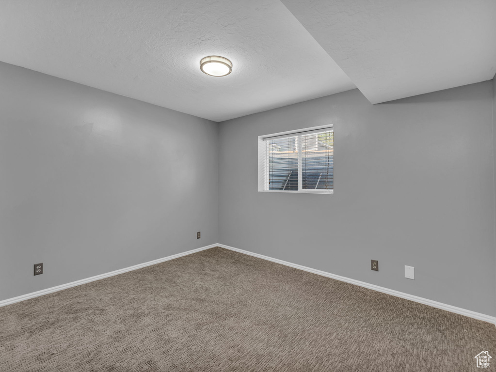 Carpeted spare room with baseboards and a textured ceiling