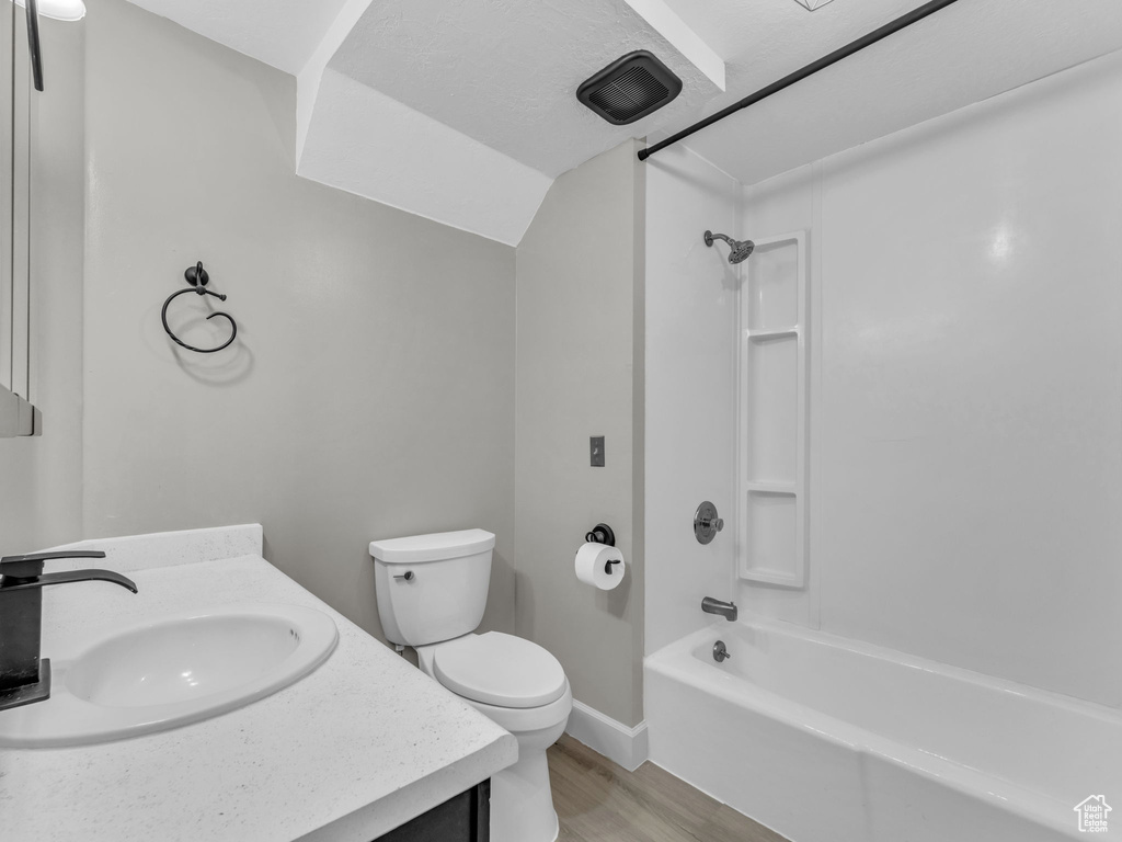 Bathroom featuring toilet, wood finished floors, vanity, shower / washtub combination, and baseboards