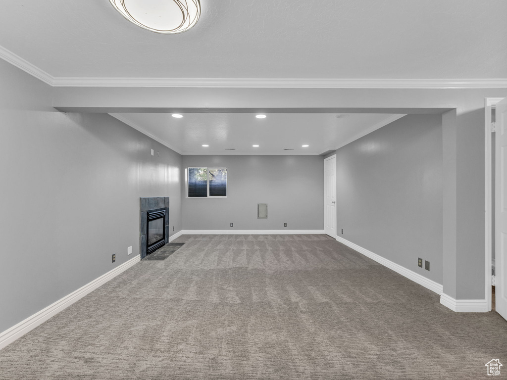 Basement with carpet, ornamental molding, recessed lighting, a tiled fireplace, and baseboards