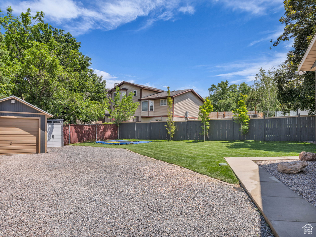 View of yard featuring an outdoor structure, a detached garage, and gravel driveway
