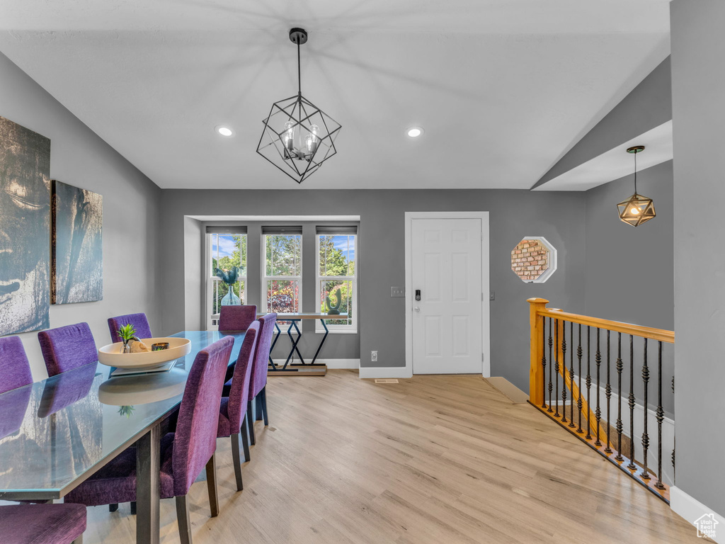 Dining area featuring lofted ceiling, wood finished floors, a chandelier, baseboards, and recessed lighting