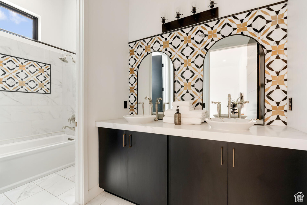 Bathroom featuring double vanity, shower / bath combination, and marble finish floors