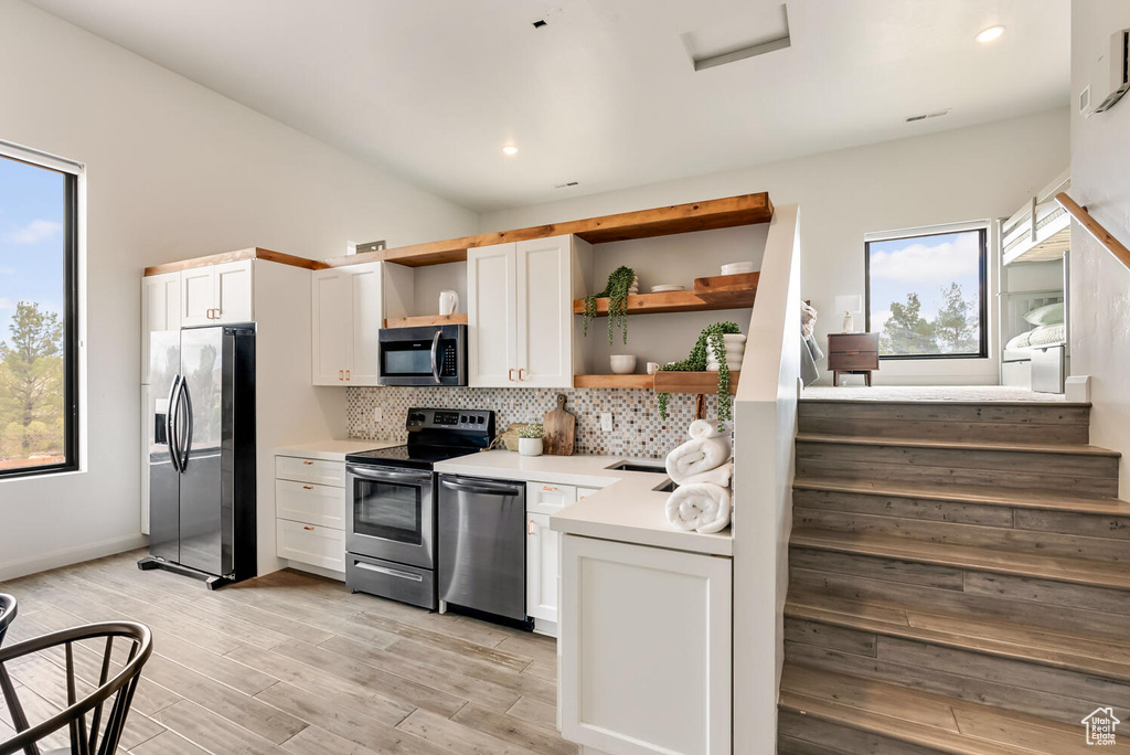 Kitchen with appliances with stainless steel finishes, open shelves, tasteful backsplash, plenty of natural light, and recessed lighting