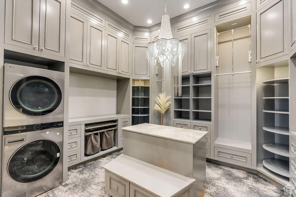 Laundry area with stacked washing machine and dryer, a chandelier, recessed lighting, and cabinet space