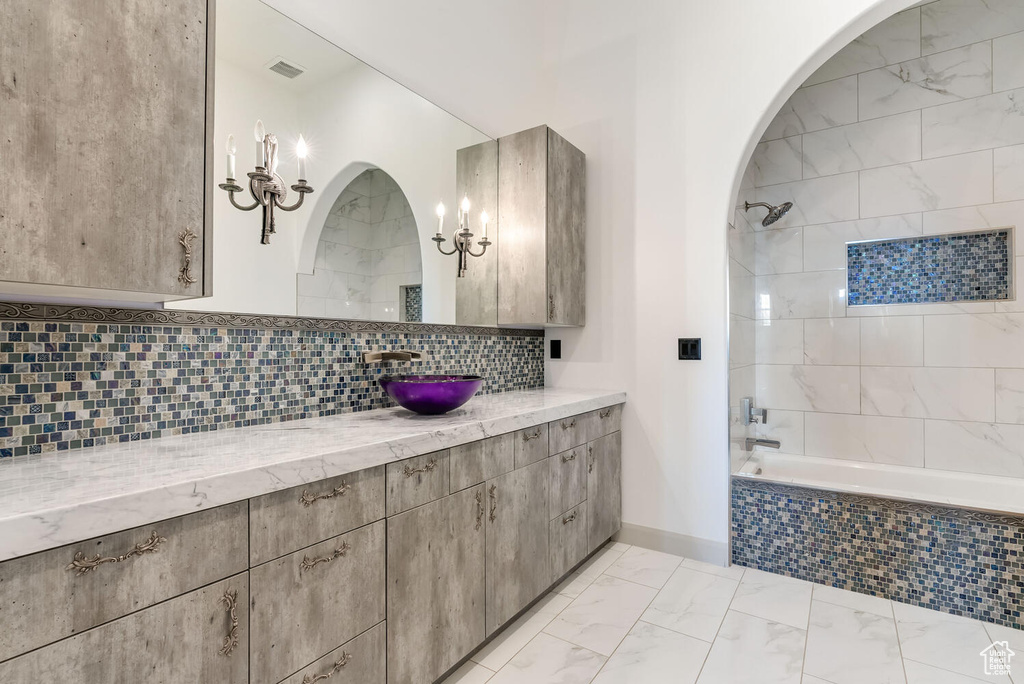Full bathroom featuring vanity, tiled shower / bath, backsplash, and marble look tiles