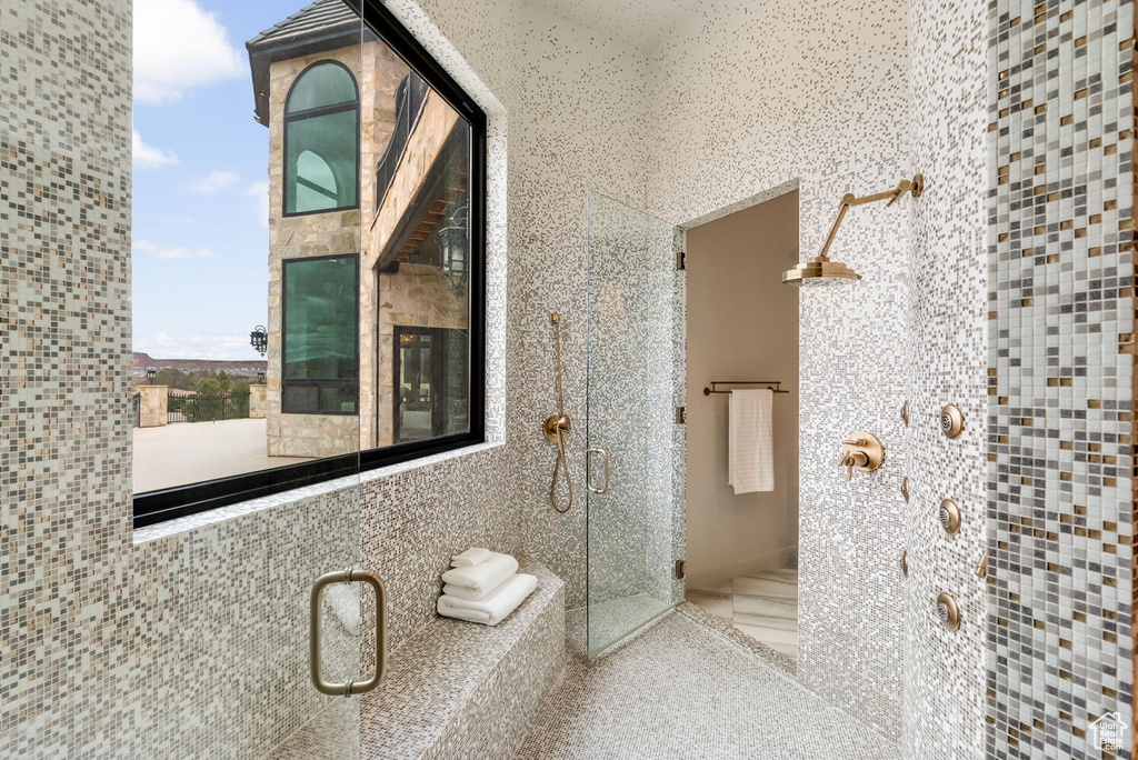 Full bathroom featuring a shower stall and tile walls