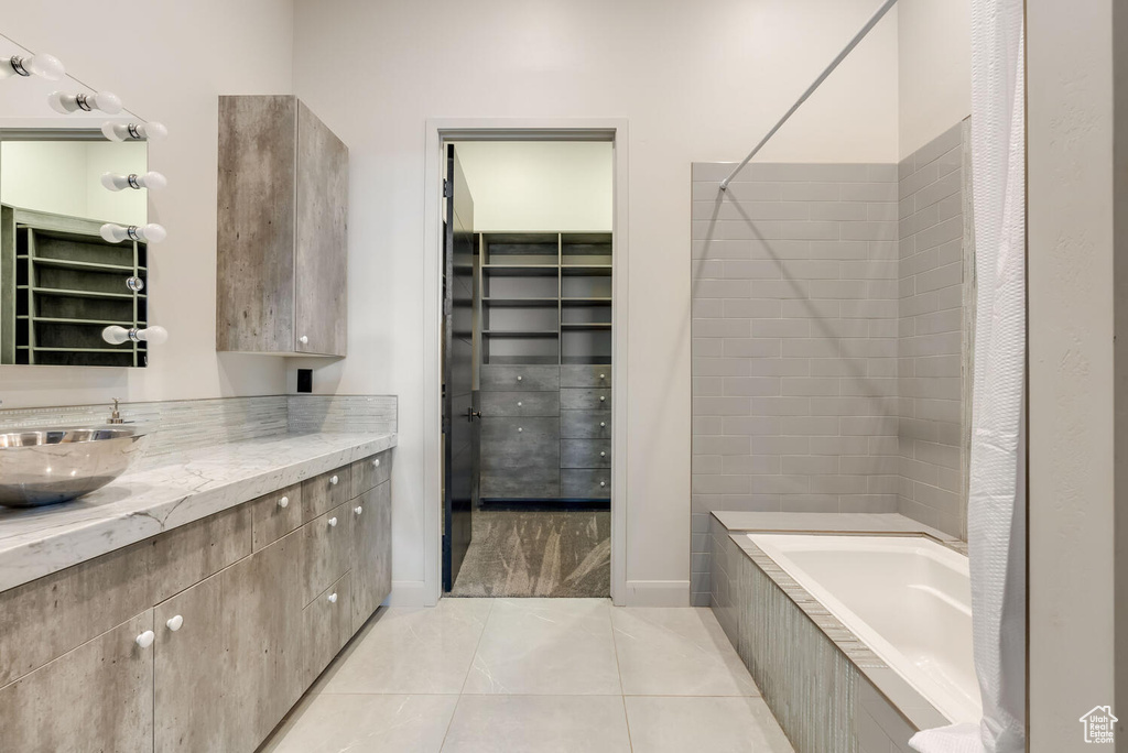Full bathroom with vanity, a walk in closet, tile patterned flooring, and tiled shower / bath combo