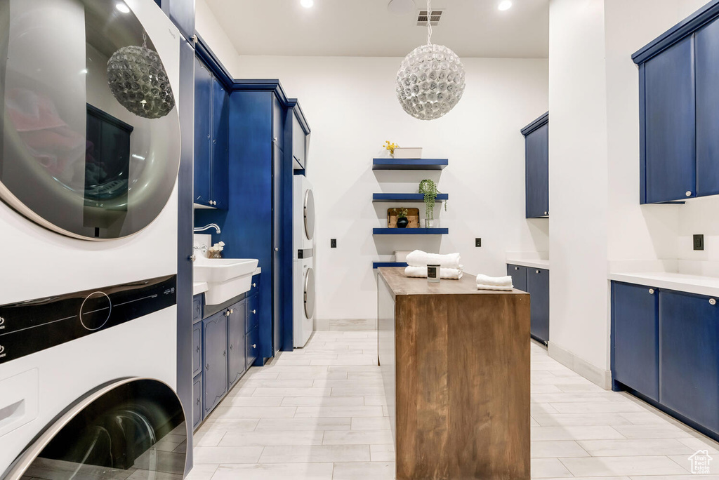 Washroom with stacked washer and clothes dryer, cabinet space, a chandelier, and recessed lighting