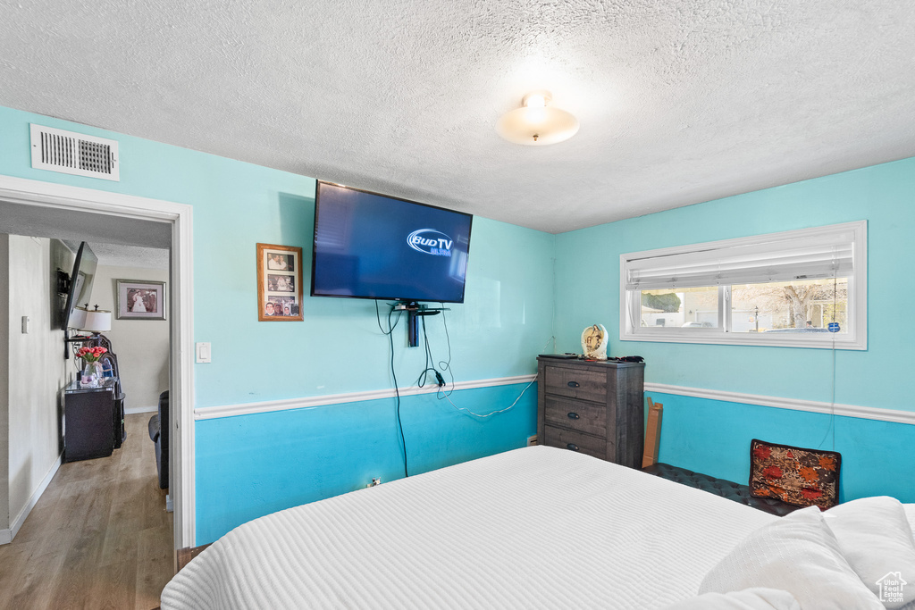 Bedroom featuring wood finished floors, a textured ceiling, and baseboards