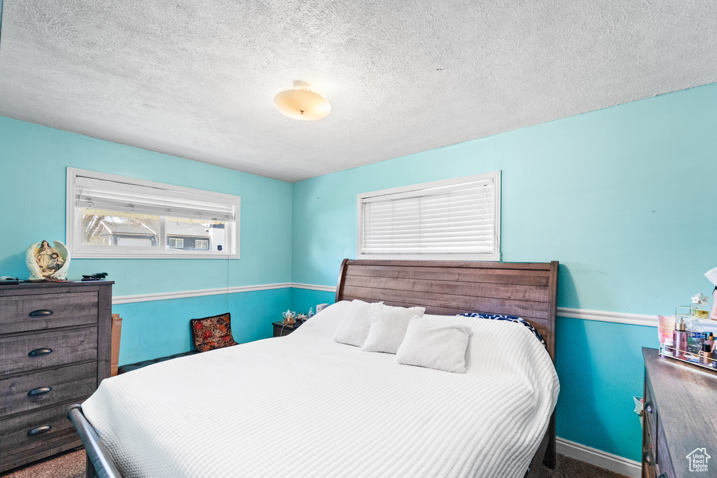 Bedroom featuring a textured ceiling, baseboards, and carpet flooring