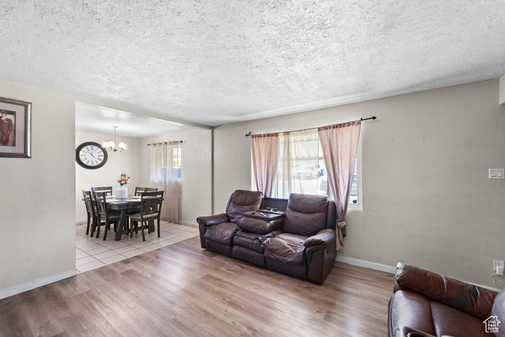 Living area featuring a textured ceiling, a chandelier, wood finished floors, and baseboards