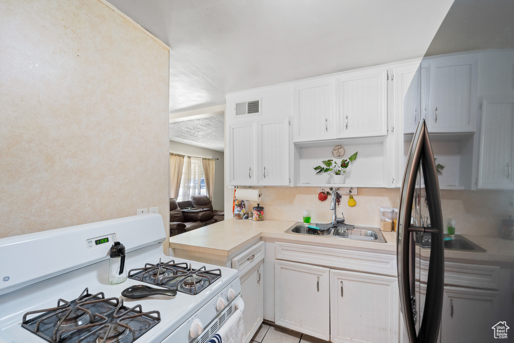 Kitchen featuring gas range gas stove, open shelves, light countertops, and white cabinets