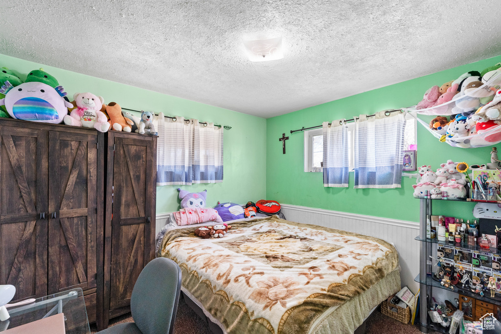 Bedroom featuring a wainscoted wall and a textured ceiling