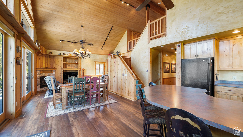 Dining space with wood ceiling, high vaulted ceiling, dark wood-style floors, track lighting, and baseboards