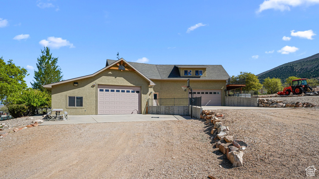 View of front facade featuring concrete driveway, an attached garage, a mountain view, and stucco siding