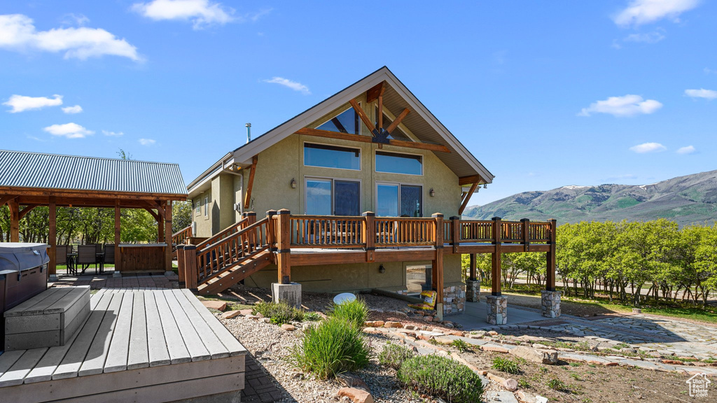 Rear view of property featuring a deck with mountain view, stucco siding, and a patio area
