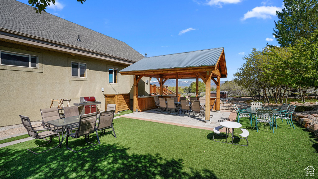 View of grassy yard featuring outdoor dining area, a gazebo, and a patio area