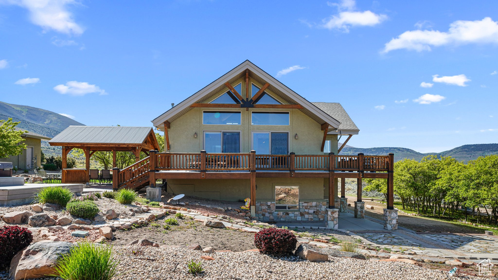Chalet / cabin featuring stucco siding, a deck with mountain view, and a patio