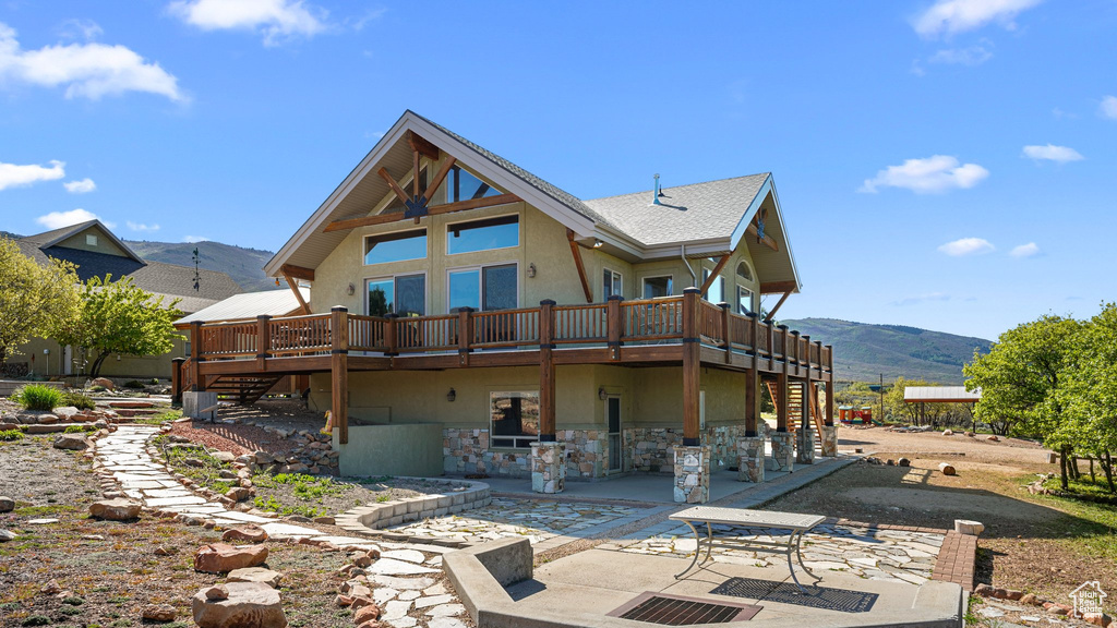 Back of property featuring stairs, stucco siding, a patio area, and a deck with mountain view