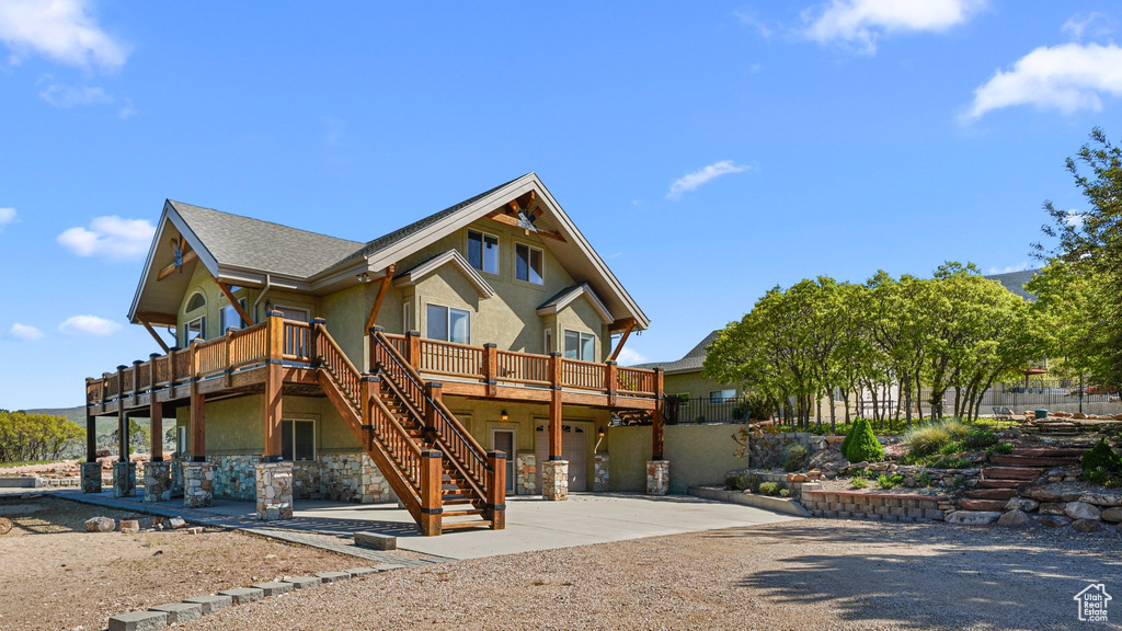 View of front facade with concrete driveway, stairway, a wooden deck, stone siding, and a garage