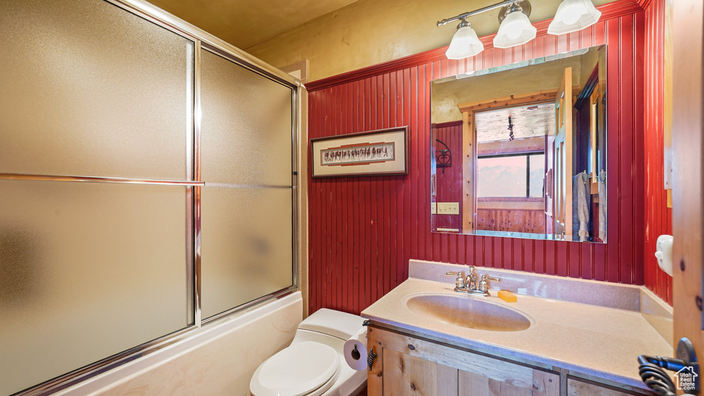 Bathroom featuring toilet, vanity, and combined bath / shower with glass door