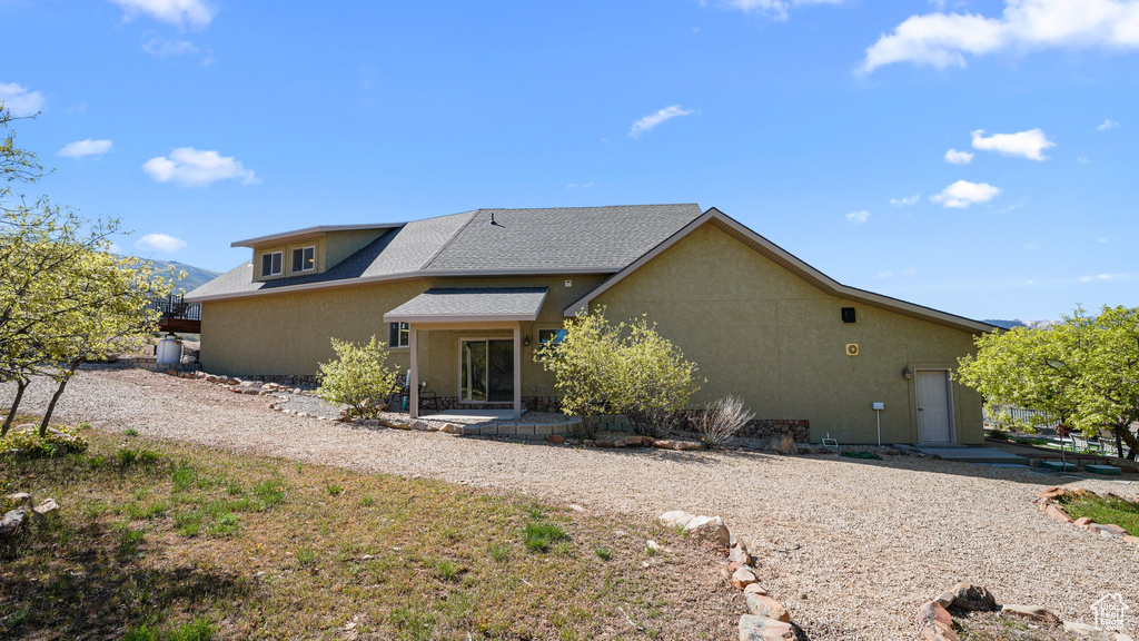 Rear view of house with stucco siding and a shingled roof