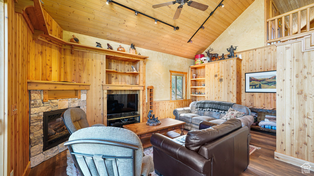 Living room with rail lighting, wood walls, wooden ceiling, a fireplace, and a ceiling fan
