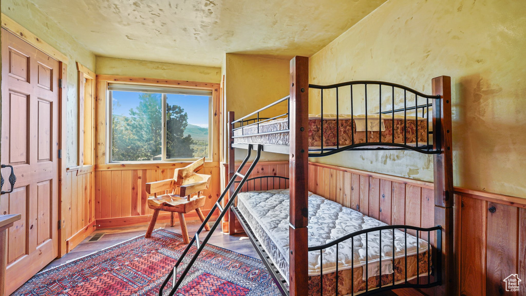 Bedroom featuring wainscoting, wood finished floors, and wooden walls