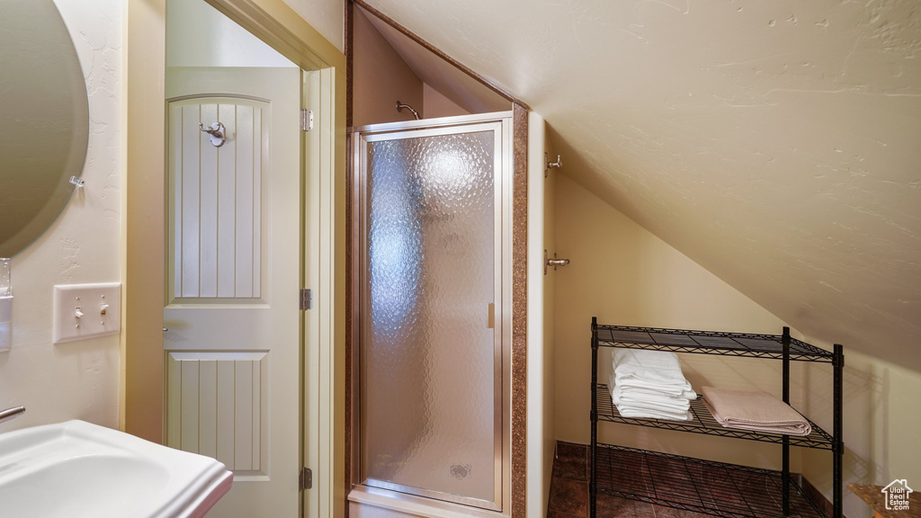 Bathroom featuring lofted ceiling, a shower stall, and a sink