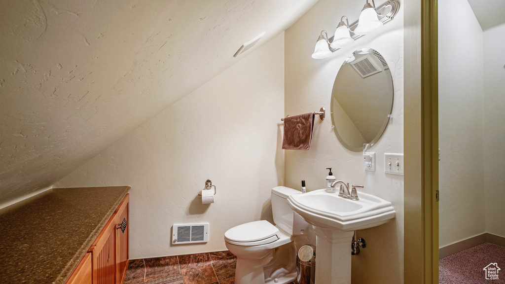 Bathroom featuring lofted ceiling, toilet, baseboards, and a sink