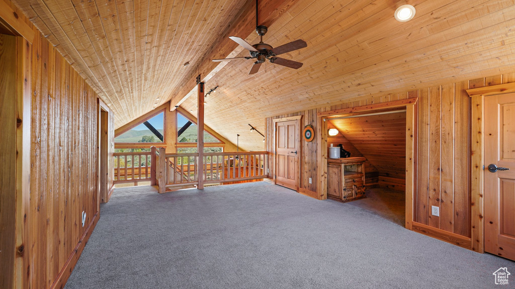 Bonus room with a ceiling fan, wooden walls, carpet, and wood ceiling