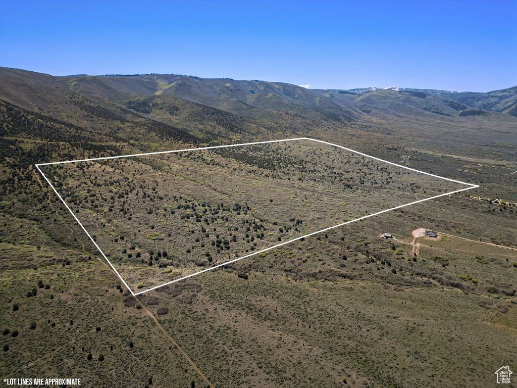 Aerial view of sparsely populated area featuring property parcel outlined and a mountainous background