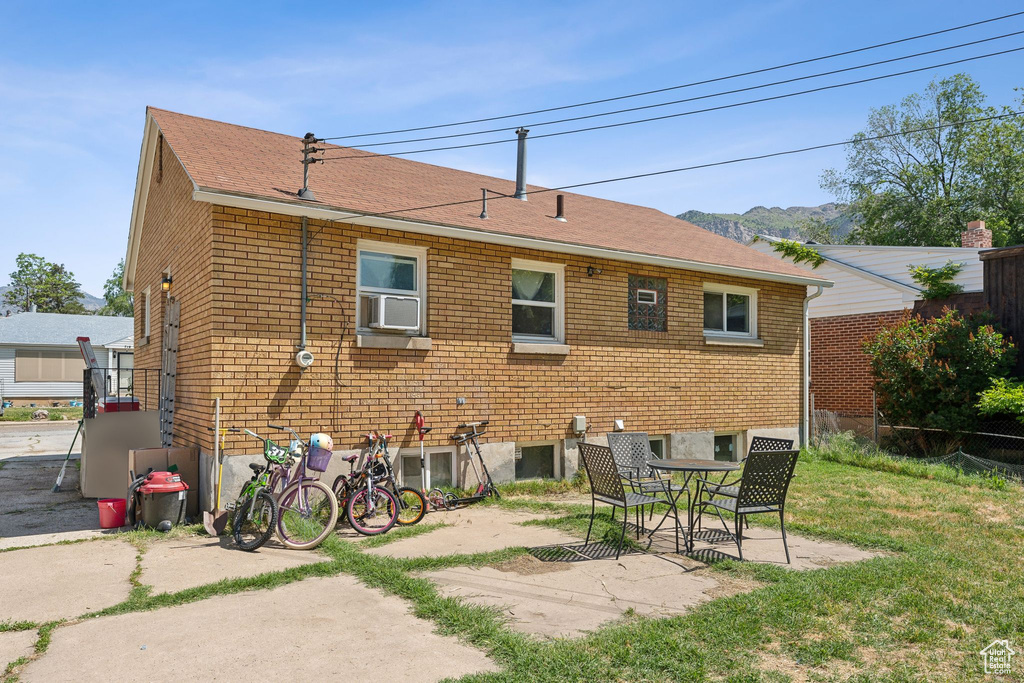 Back of property featuring a patio, brick siding, a shingled roof, and cooling unit
