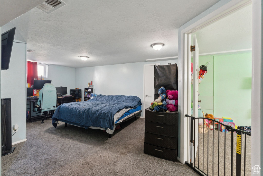 Bedroom featuring carpet, an office area, and a textured ceiling
