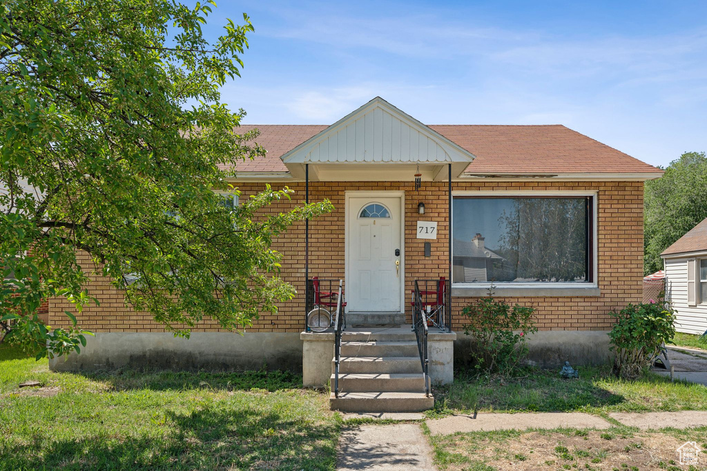 View of front of home with brick siding and roof with shingles