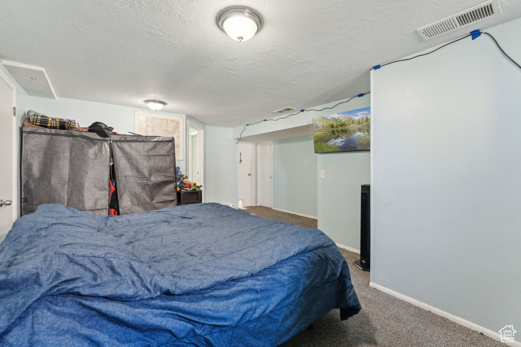 Bedroom with baseboards, carpet floors, and a textured ceiling