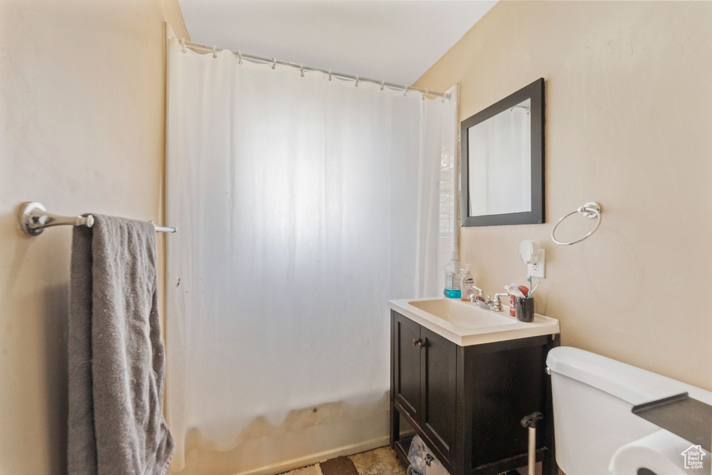 Bathroom with vanity, shower / bath combo, and toilet