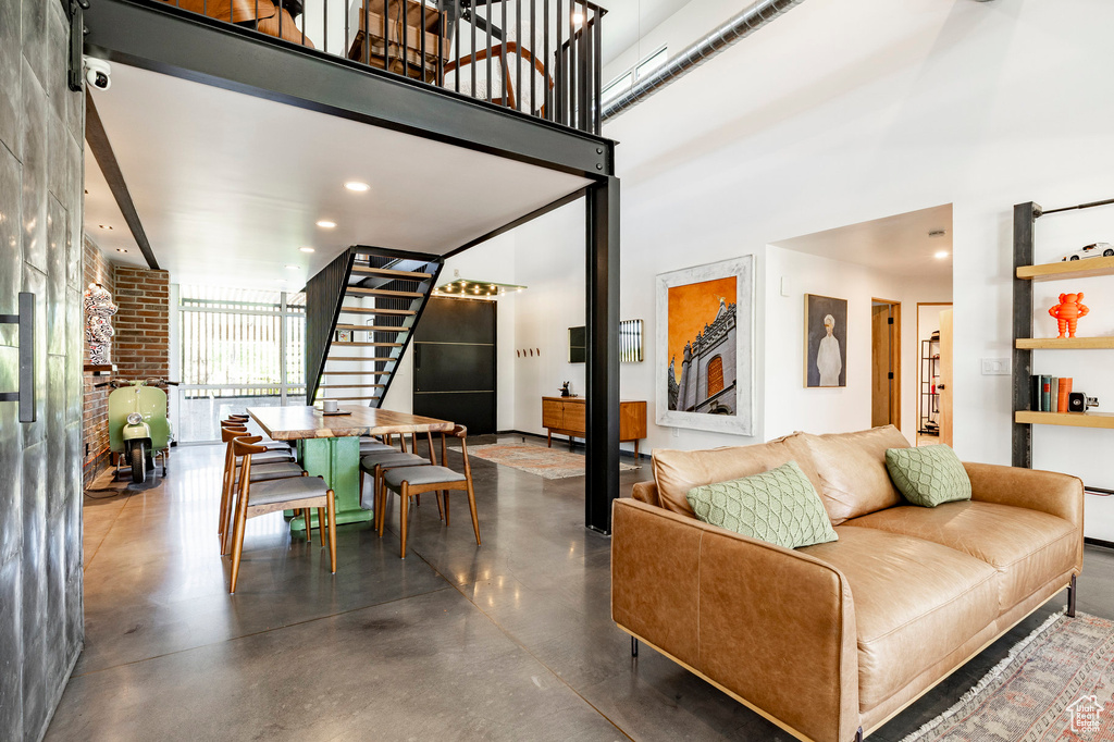 Living area with stairway, concrete floors, a towering ceiling, and recessed lighting