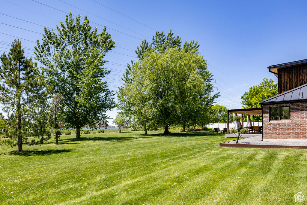 View of grassy yard featuring a patio