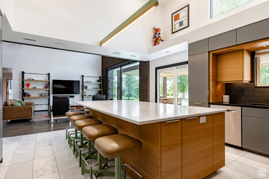 Kitchen featuring a high ceiling, a center island, open floor plan, stainless steel dishwasher, and modern cabinets