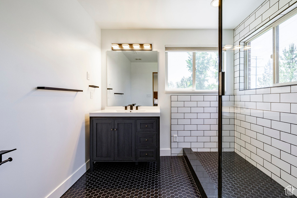 Bathroom with a walk in shower, vanity, tile patterned flooring, and baseboards